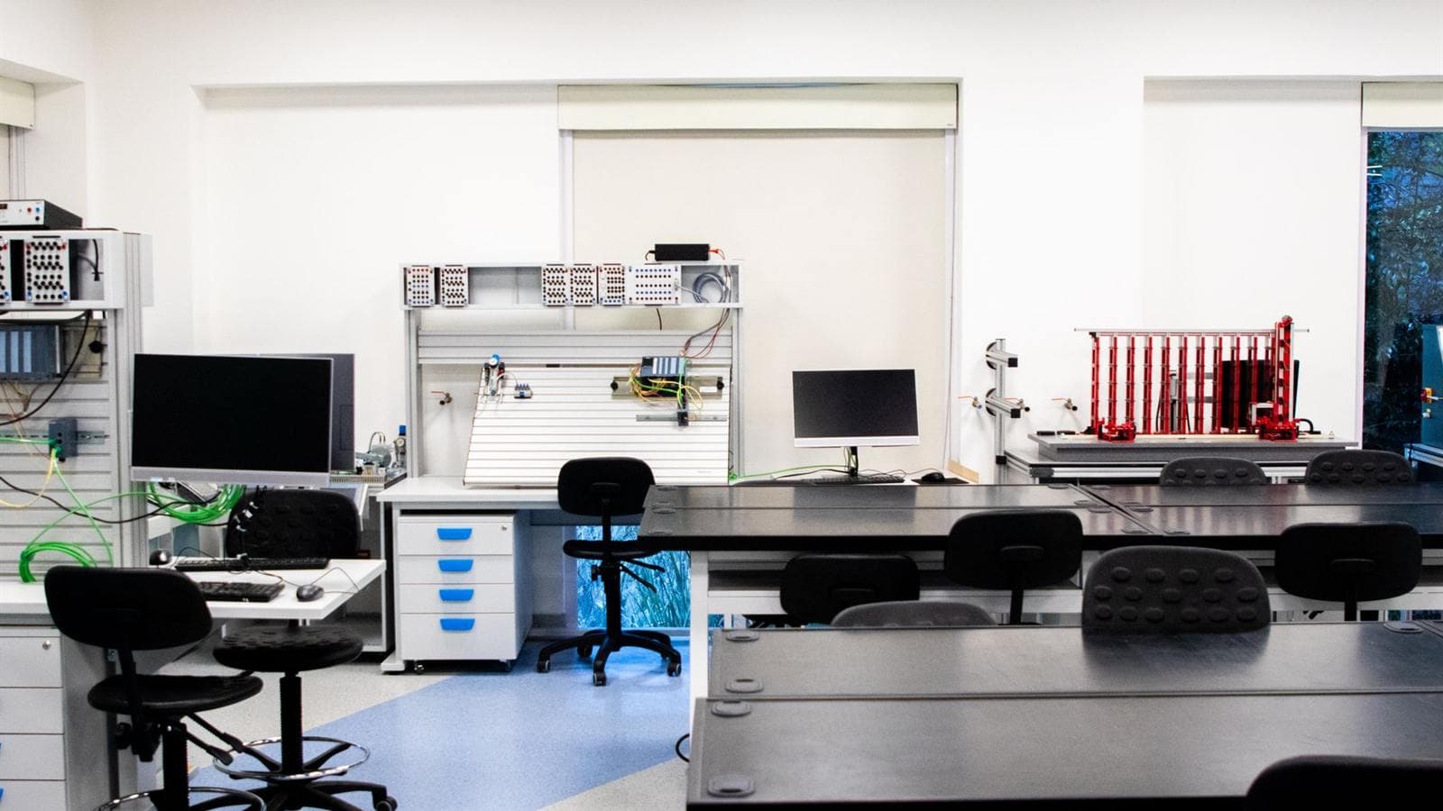 A bright engineering laboratory with workbenches, monitors, and test equipment.