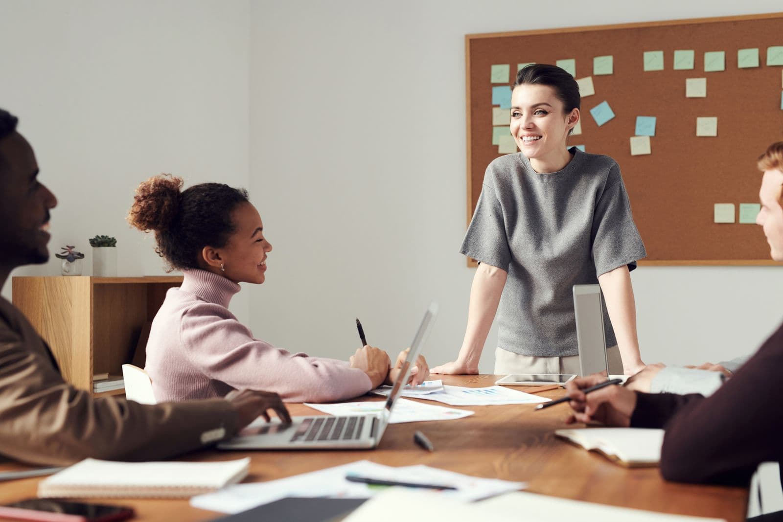 A person presenting to seated colleagues in a meeting room.