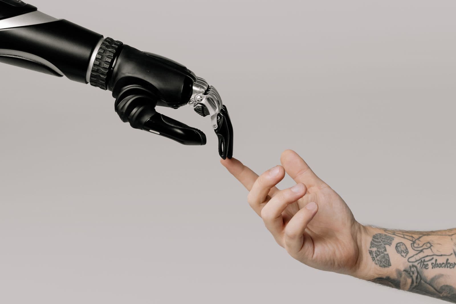 A robotic hand and a human hand reaching toward one another.